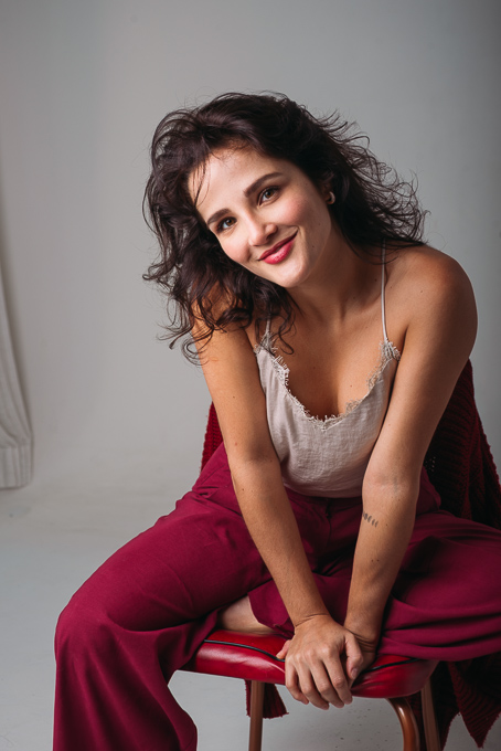 Juliane Portella sentada em uma cadeira vermelha